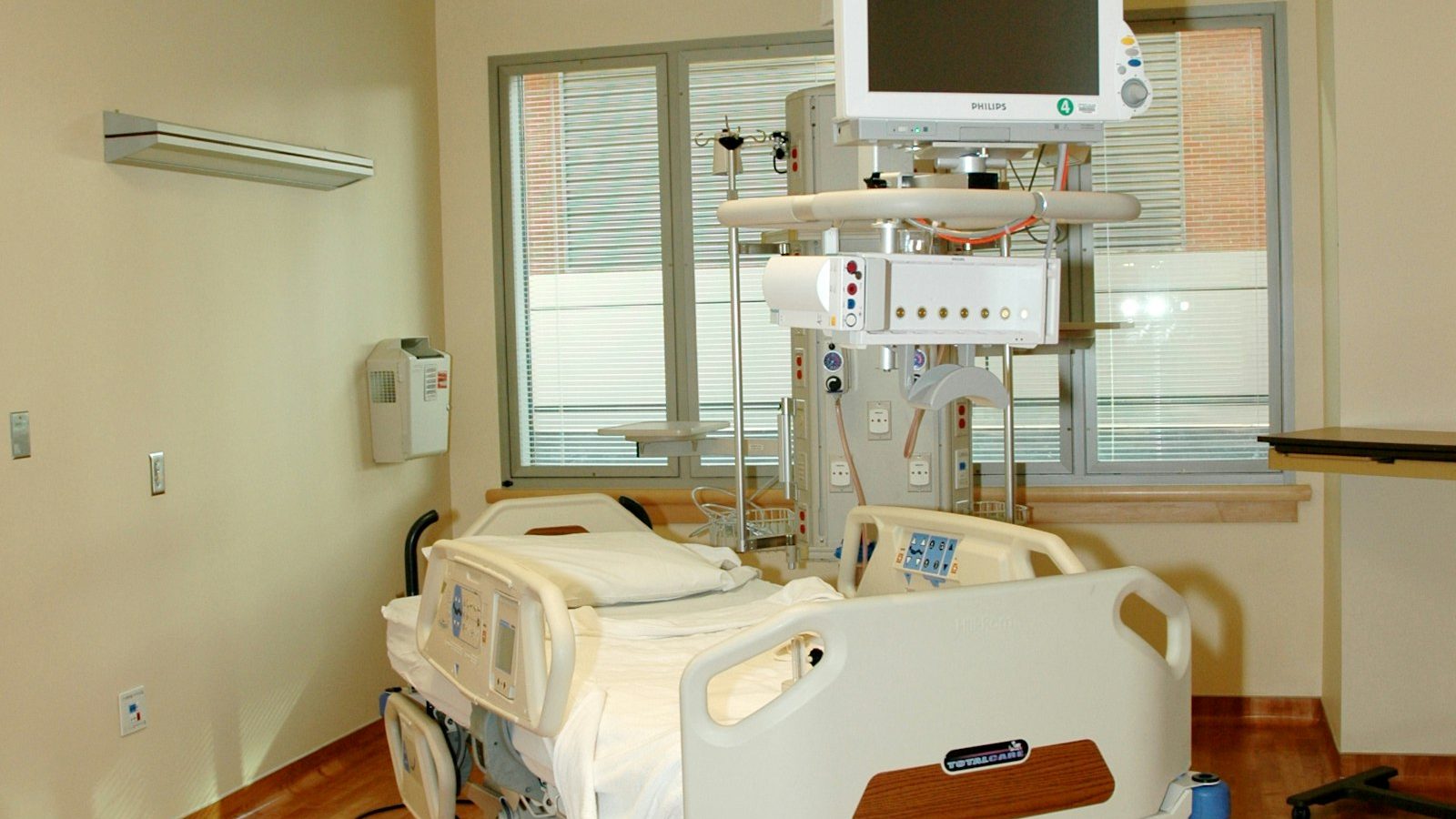 An empty hospital room with a bed by the window