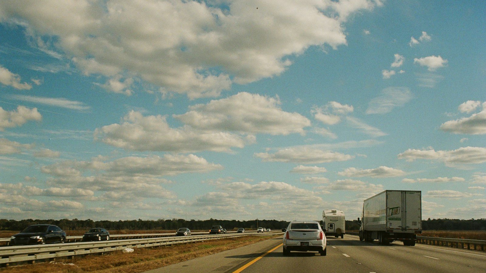 A tractor-trailer on an interstate highway under a Florida sky